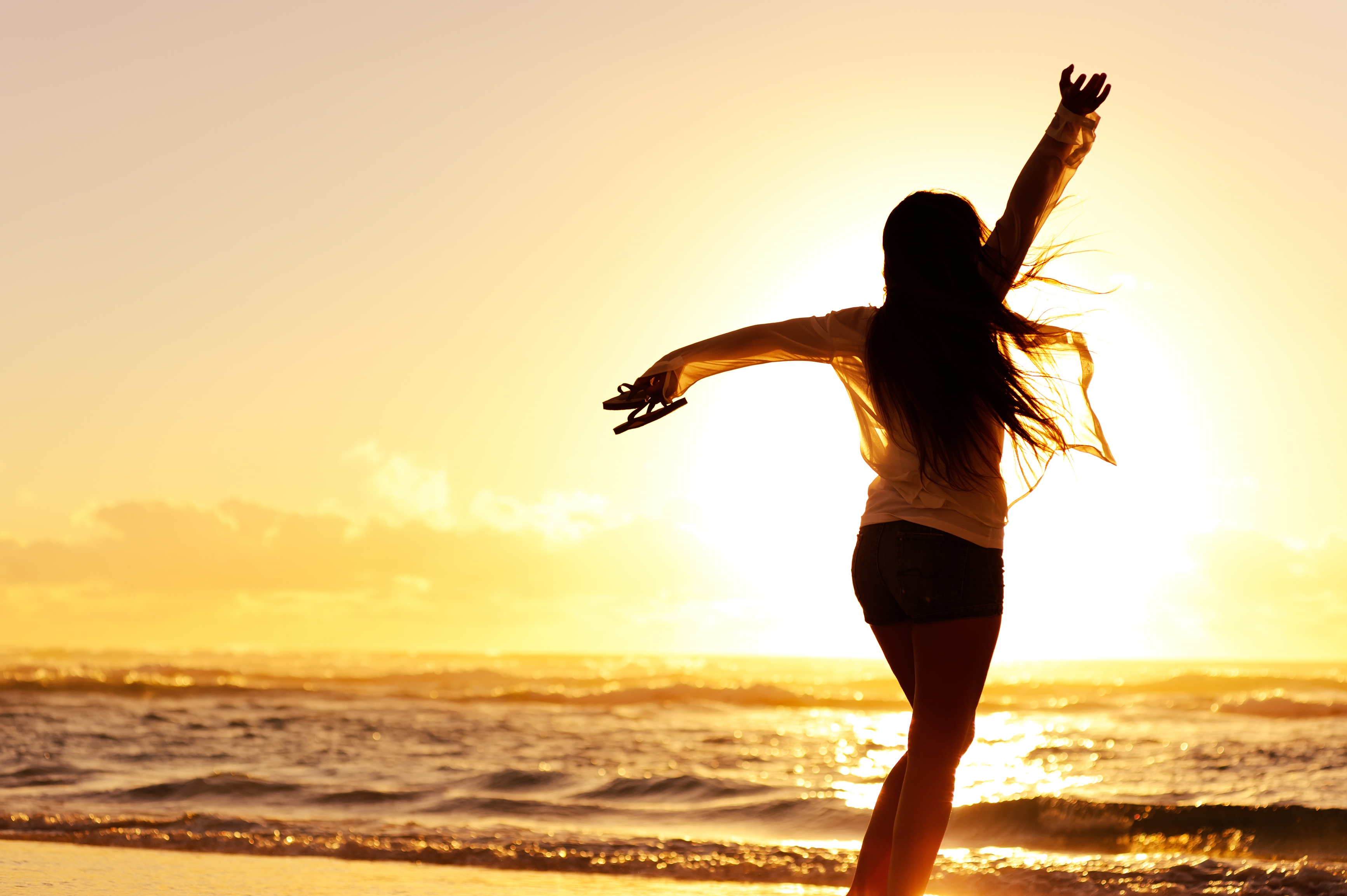 carefree woman dancing in the sunset on the beach. vacation vitality healthy living concept